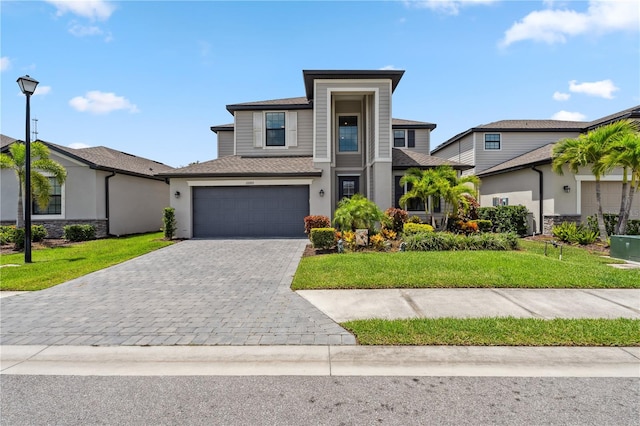11105 Balfour St E, Venice, FL 34293 - view of front of house featuring decorative driveway, a front yard, an attached garage, and stucco siding