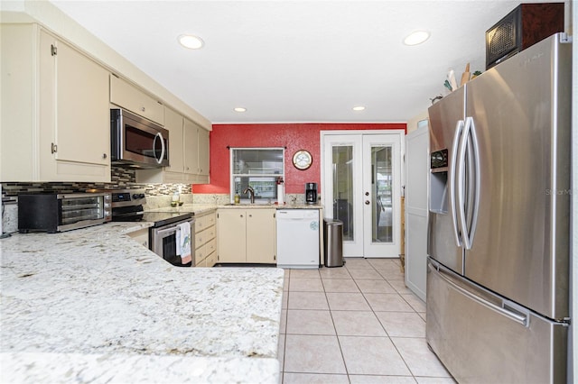 4051 Rock Creek Dr, Port Charlotte, FL 33948 - kitchen featuring appliances with stainless steel finishes, cream cabinetry, recessed lighting, light tile patterned flooring, and french doors