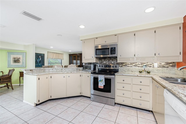 4051 Rock Creek Dr, Port Charlotte, FL 33948 - kitchen with appliances with stainless steel finishes, a peninsula, tasteful backsplash, light tile patterned floors, and recessed lighting