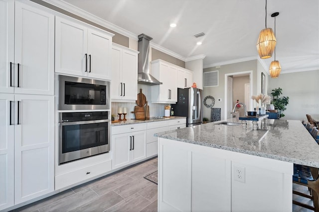14436 Ponce De Leon Trl, Port Charlotte, FL 33981 - kitchen with stainless steel appliances, wall chimney range hood, a kitchen bar, white cabinets, and crown molding
