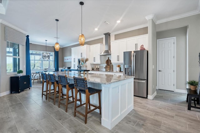 14436 Ponce De Leon Trl, Port Charlotte, FL 33981 - kitchen featuring stainless steel fridge, wall chimney range hood, a spacious island, white cabinetry, and a kitchen bar
