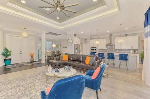 6444 Alhambra Ave, North Port, FL 34291 - living room with ornate columns, a tray ceiling, light wood-type flooring, ceiling fan, and crown molding