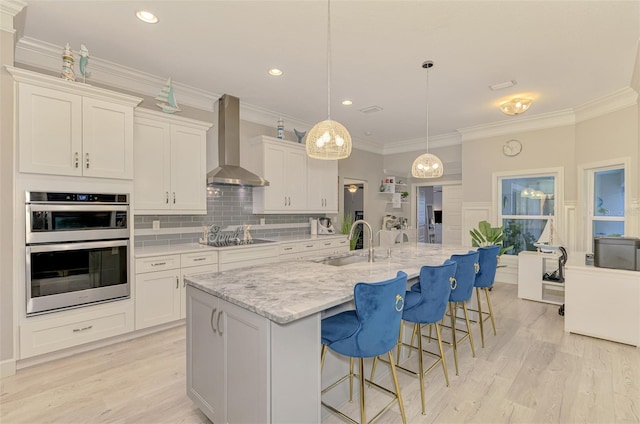 6444 Alhambra Ave, North Port, FL 34291 - kitchen featuring wall chimney range hood, stainless steel double oven, white cabinets, light wood-style flooring, and black electric cooktop
