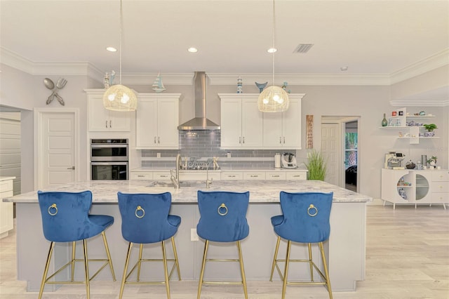 6444 Alhambra Ave, North Port, FL 34291 - kitchen featuring wall chimney range hood, double oven, white cabinets, a large island with sink, and backsplash