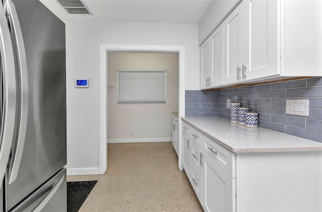 4244 Harbor Blvd, Port Charlotte, FL 33952 - kitchen with freestanding refrigerator, backsplash, white cabinetry, light stone countertops, and dark speckled floor