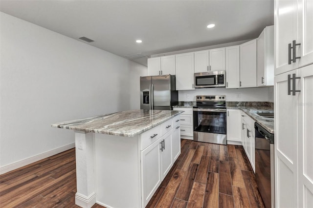 419 Carmalita St, Punta Gorda, FL 33950 - kitchen with appliances with stainless steel finishes, dark wood-style flooring, a kitchen island, light stone countertops, and recessed lighting