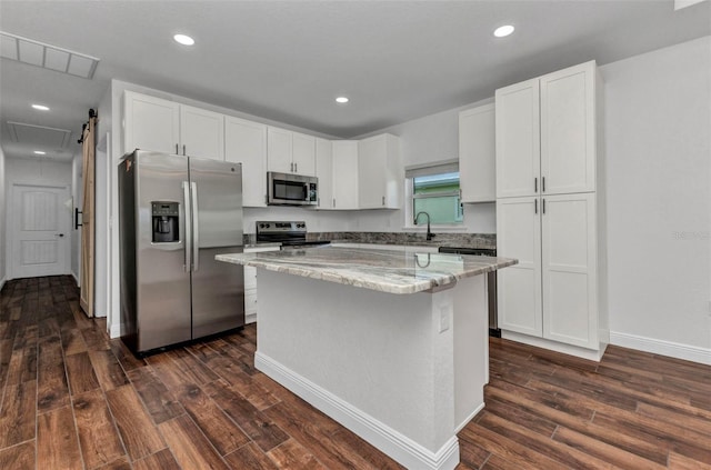 419 Carmalita St, Punta Gorda, FL 33950 - kitchen with appliances with stainless steel finishes, dark wood-type flooring, white cabinets, light stone countertops, and a kitchen island