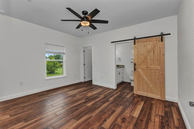419 Carmalita St, Punta Gorda, FL 33950 - unfurnished bedroom with a barn door, dark wood-type flooring, ensuite bathroom, and a ceiling fan