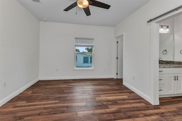 419 Carmalita St, Punta Gorda, FL 33950 - unfurnished bedroom featuring dark wood-style flooring, a barn door, connected bathroom, and ceiling fan