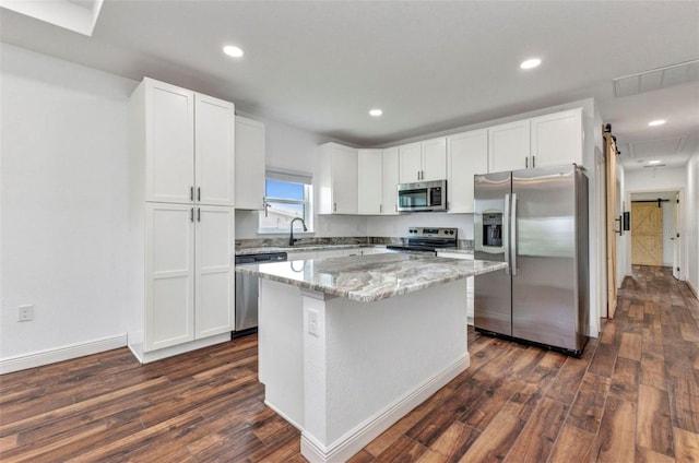 419 Carmalita St, Punta Gorda, FL 33950 - kitchen with stainless steel appliances, dark wood-style floors, a center island, white cabinetry, and light stone counters