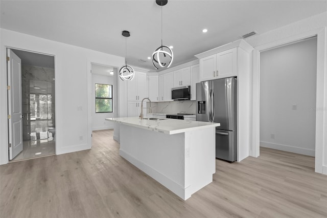 17156 Eugene Ave, Port Charlotte, FL 33954 - kitchen featuring appliances with stainless steel finishes, light wood-style flooring, white cabinetry, a center island with sink, and recessed lighting