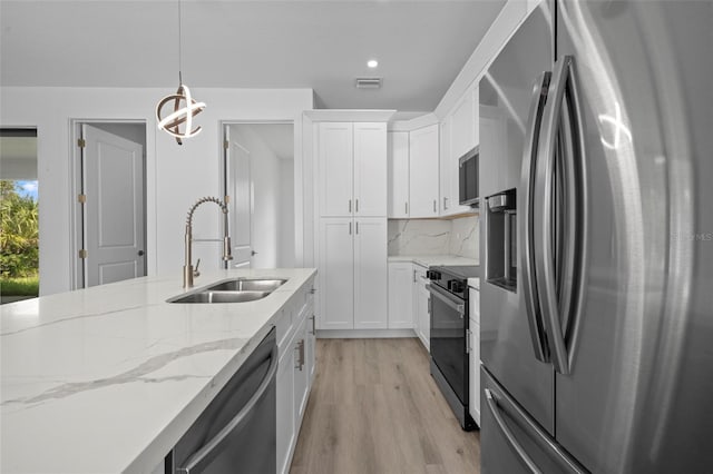 17156 Eugene Ave, Port Charlotte, FL 33954 - kitchen with appliances with stainless steel finishes, light wood finished floors, tasteful backsplash, white cabinetry, and light stone counters