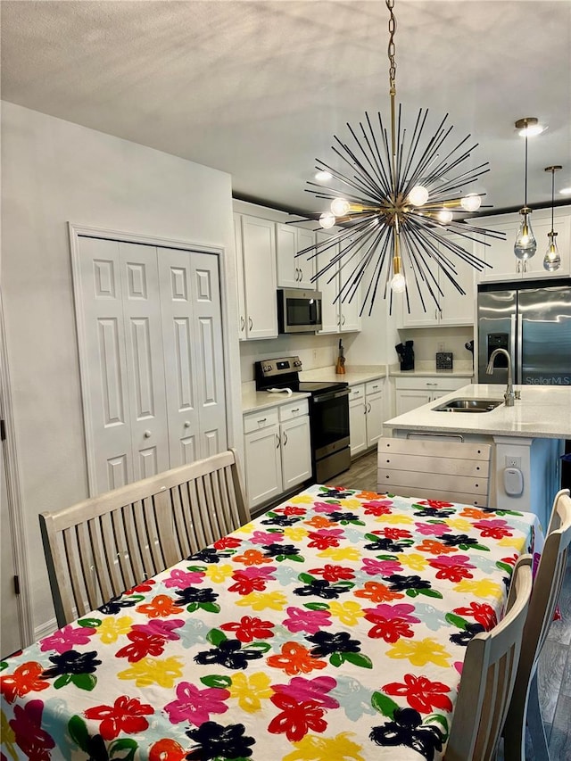 1992 Sunset Preserve Way, Port Charlotte, FL 33953 - kitchen with stainless steel appliances, a chandelier, a kitchen island with sink, white cabinets, and pendant lighting