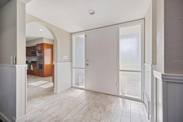 2309 Conway Blvd, Port Charlotte, FL 33952 - entryway featuring light wood-style flooring, a wainscoted wall, arched walkways, and a decorative wall