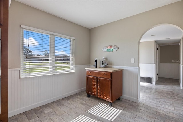2309 Conway Blvd, Port Charlotte, FL 33952 - bar featuring wainscoting, light wood-type flooring, arched walkways, and plenty of natural light