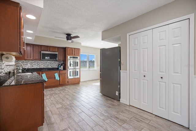 2309 Conway Blvd, Port Charlotte, FL 33952 - kitchen featuring appliances with stainless steel finishes, a textured ceiling, a ceiling fan, tasteful backsplash, and brown cabinets
