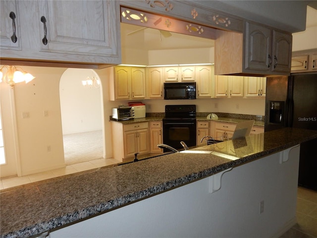 388 Orlando Blvd, Port Charlotte, FL 33954 - kitchen with black appliances, a breakfast bar, light tile patterned floors, a chandelier, and dark stone counters