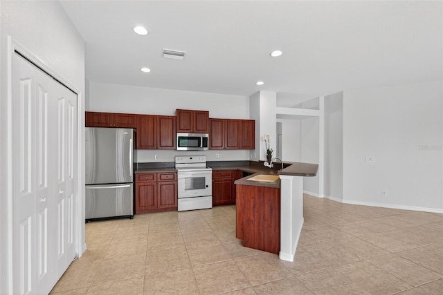 1762 Mincey Ter, North Port, FL 34286 - kitchen featuring stainless steel appliances, dark countertops, a peninsula, light tile patterned floors, and recessed lighting