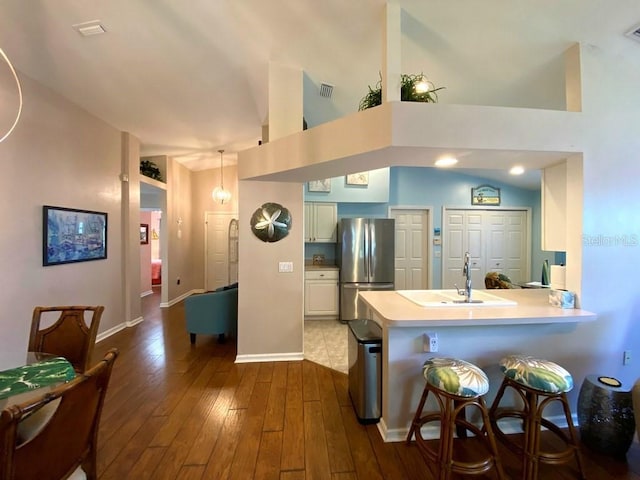 24132 Buckingham Way, Punta Gorda, FL 33980 - kitchen featuring freestanding refrigerator, a peninsula, light countertops, dark wood-style flooring, and a breakfast bar