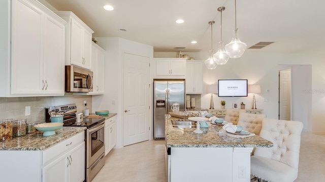 2308 Oberon Ln, Punta Gorda, FL 33983 - kitchen with stainless steel appliances, an island with sink, tasteful backsplash, white cabinetry, and recessed lighting