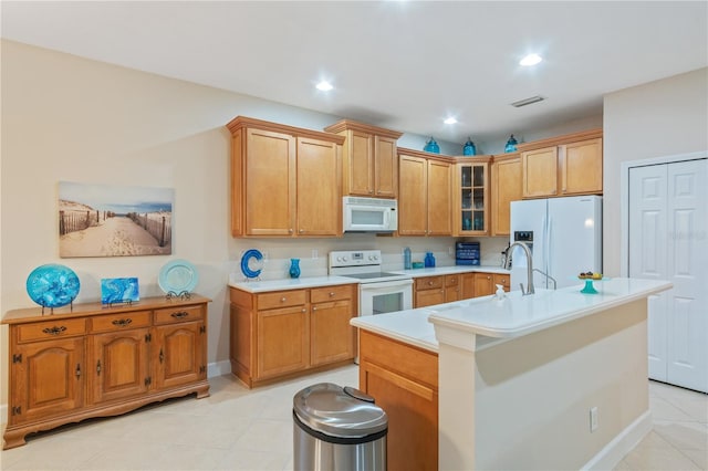 2712 Arugula Dr, North Port, FL 34289 - kitchen with white appliances, light tile patterned floors, light countertops, glass insert cabinets, and an island with sink