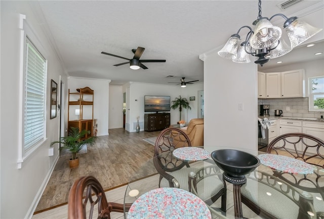 21539 Gladis Ave, Port Charlotte, FL 33952 - dining room featuring light wood-style flooring, a ceiling fan, crown molding, a chandelier, and a textured ceiling