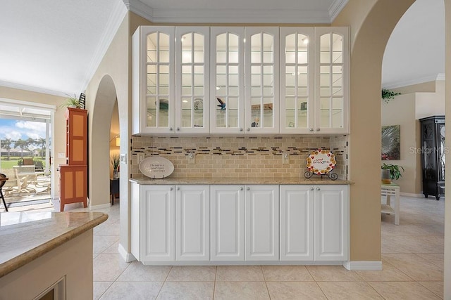 3385 Via Montana Way N, Fort Myers, FL 33917 - bar area featuring arched walkways, ornamental molding, light tile patterned floors, and backsplash