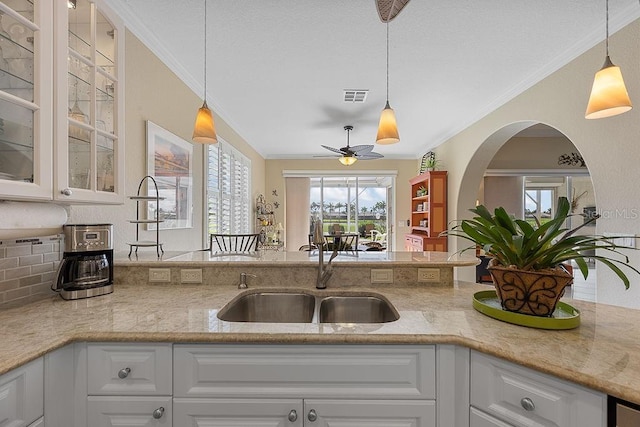 3385 Via Montana Way N, Fort Myers, FL 33917 - kitchen featuring ornamental molding, glass insert cabinets, ceiling fan, white cabinets, and light stone countertops