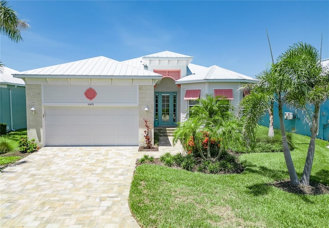 10478 Coquina Ct, Placida, FL 33946 - view of front of house featuring a standing seam roof, a metal roof, decorative driveway, an attached garage, and a front lawn