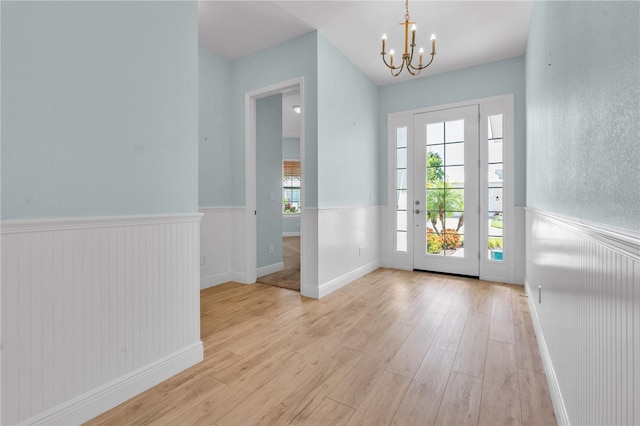 10478 Coquina Ct, Placida, FL 33946 - doorway featuring wainscoting, a chandelier, and light wood-style floors