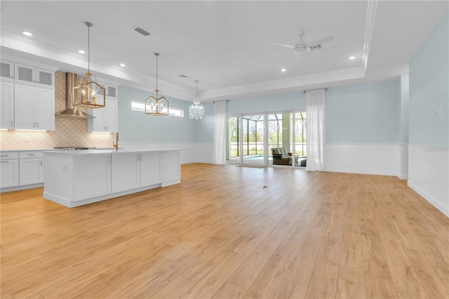 10478 Coquina Ct, Placida, FL 33946 - kitchen featuring wall chimney exhaust hood, open floor plan, a chandelier, light wood finished floors, and a wainscoted wall