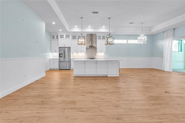 10478 Coquina Ct, Placida, FL 33946 - kitchen with stainless steel fridge with ice dispenser, wall chimney exhaust hood, white cabinets, light countertops, and light wood-style floors