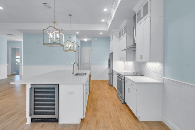 10478 Coquina Ct, Placida, FL 33946 - kitchen with appliances with stainless steel finishes, wine cooler, wall chimney exhaust hood, crown molding, and a center island with sink