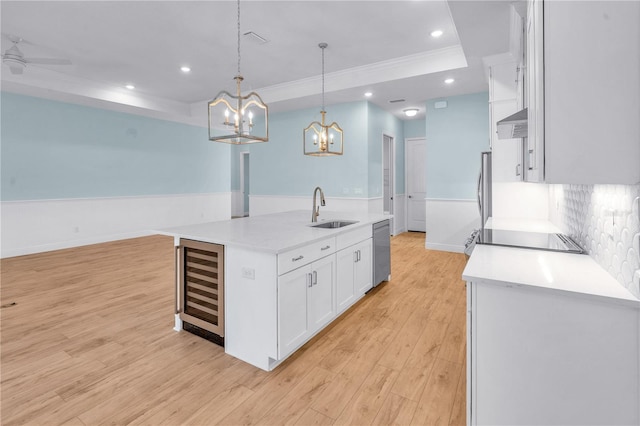 10478 Coquina Ct, Placida, FL 33946 - kitchen with beverage cooler, appliances with stainless steel finishes, white cabinetry, an island with sink, and a raised ceiling