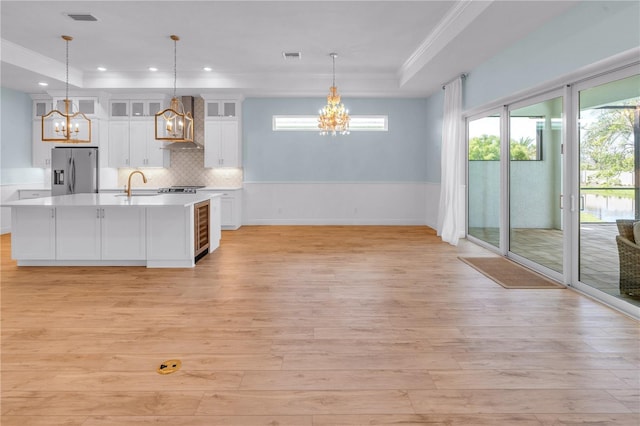 10478 Coquina Ct, Placida, FL 33946 - kitchen with stainless steel fridge with ice dispenser, a chandelier, light wood-style floors, wall chimney range hood, and crown molding