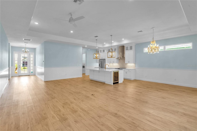 10478 Coquina Ct, Placida, FL 33946 - unfurnished living room with a chandelier, a raised ceiling, wine cooler, a wainscoted wall, and recessed lighting