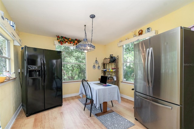 6605 NE Masters Ave, Arcadia, FL 34266 - kitchen featuring freestanding refrigerator, black refrigerator with ice dispenser, light wood-type flooring, and decorative light fixtures