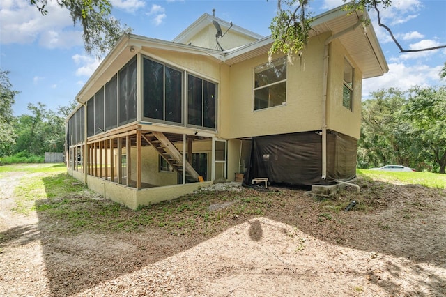6605 NE Masters Ave, Arcadia, FL 34266 - back of house featuring a sunroom, stucco siding, and stairway