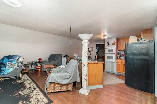 6605 NE Masters Ave, Arcadia, FL 34266 - kitchen with freestanding refrigerator, open floor plan, light wood-style floors, decorative columns, and white double oven