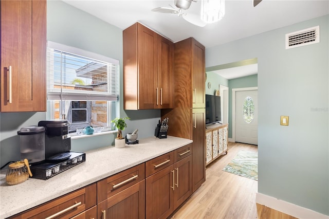 1027 Coral Ridge Dr, Punta Gorda, FL 33950 - kitchen featuring ceiling fan, light wood finished floors, light stone counters, and brown cabinetry