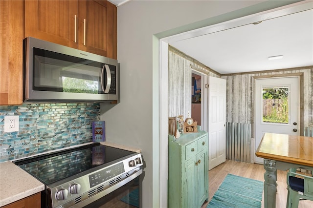 1027 Coral Ridge Dr, Punta Gorda, FL 33950 - kitchen with appliances with stainless steel finishes, decorative backsplash, light wood finished floors, and brown cabinetry