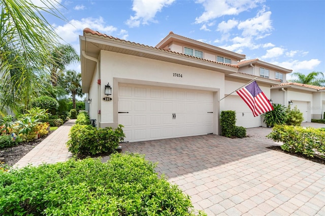 17454 Old Harmony Dr Unit 101, Fort Myers, FL 33908 - view of front facade featuring stucco siding, a garage, decorative driveway, and a tiled roof