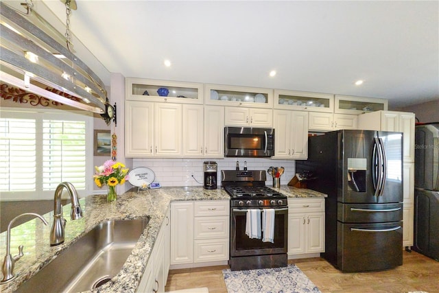 1115 San Cristobal Ave, Punta Gorda, FL 33983 - kitchen featuring stainless steel microwave, fridge with ice dispenser, range with gas stovetop, tasteful backsplash, and light stone counters