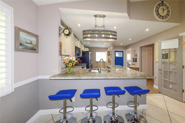 1115 San Cristobal Ave, Punta Gorda, FL 33983 - kitchen with a peninsula, light stone counters, freestanding refrigerator, light tile patterned floors, and a kitchen bar