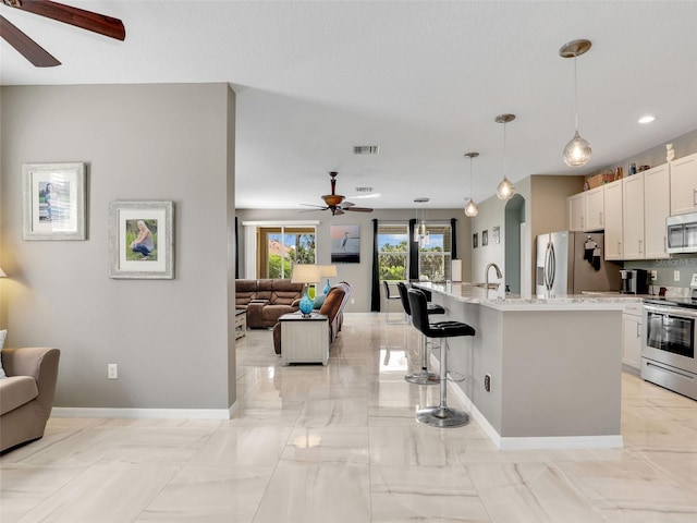 4180 Lenox Blvd, Venice, FL 34293 - kitchen featuring stainless steel appliances, ceiling fan, open floor plan, a breakfast bar area, and recessed lighting