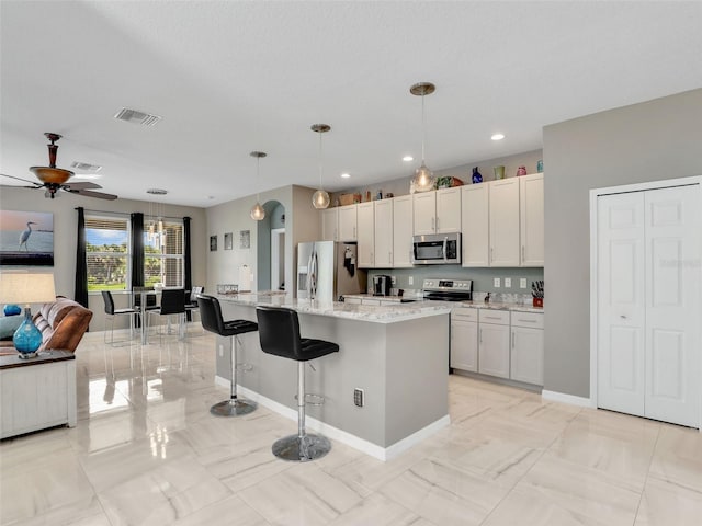 4180 Lenox Blvd, Venice, FL 34293 - kitchen with stainless steel appliances, open floor plan, ceiling fan, light stone countertops, and a kitchen bar