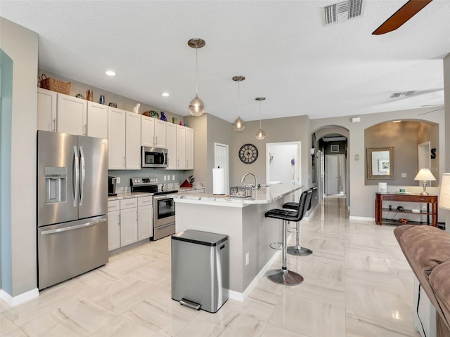 4180 Lenox Blvd, Venice, FL 34293 - kitchen featuring appliances with stainless steel finishes, arched walkways, white cabinets, a breakfast bar area, and recessed lighting
