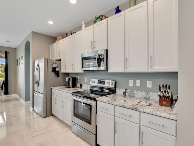4180 Lenox Blvd, Venice, FL 34293 - kitchen featuring appliances with stainless steel finishes, recessed lighting, white cabinets, light marble finish floors, and light stone countertops