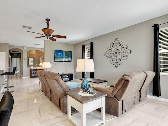 4180 Lenox Blvd, Venice, FL 34293 - living area featuring light marble finish floors, arched walkways, a ceiling fan, and healthy amount of natural light