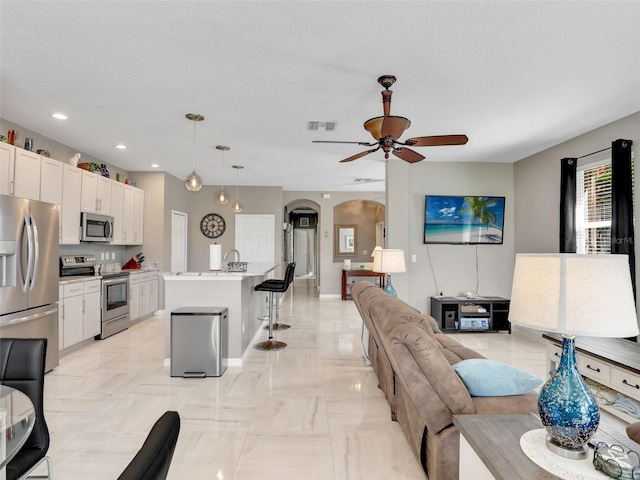 4180 Lenox Blvd, Venice, FL 34293 - living room featuring ceiling fan, arched walkways, recessed lighting, and light marble finish flooring